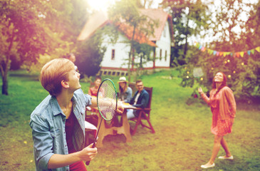 Canvas Print - happy friends playing badminton at summer garden