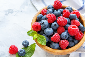 Wall Mural - Juicy raspberries and blueberries in a wooden bowl.