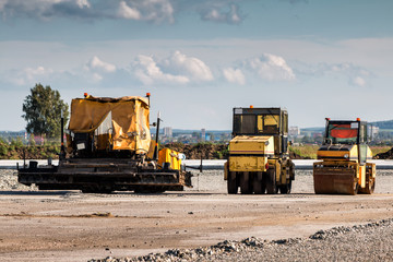 Asphalt paver and two tandem rollers for road repair