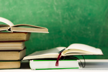 Textbooks and books on a dark wooden table. Beautiful green background.