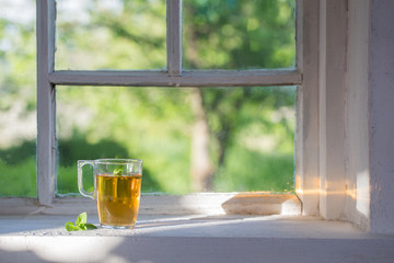 Poster - tea in glass cup on old  windowsill