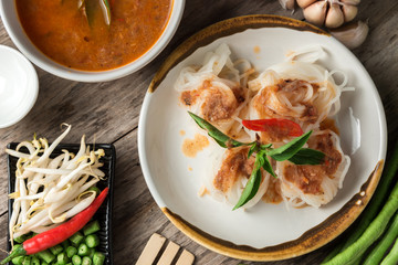 Noodle and fish curry sauce with ingredient on black table.