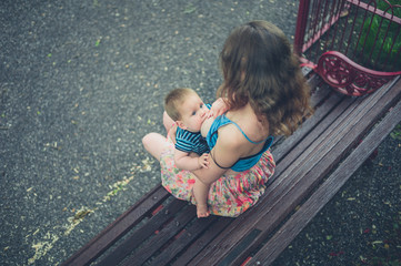 Wall Mural - Mother breastfeeding baby on park bench