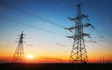 Silhouette of electricity pylons and high-voltage power lines on the field at sunset. Wire electrical energy at sunrise