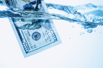 Money concept showing US Dollar sinking in water as a symbol of global economic crisis