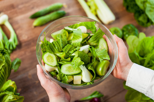 hands holding an healthy green fresh vegetarian salad in a bowl