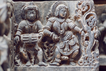 Wall Mural - Indian architecture background on traditional style relief, with drummer musician and dancing woman inside the 12th century Hoysaleshwara temple in Halebidu, India.