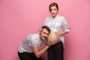 Wall Mural - Handsome man is listening to his beautiful pregnant wife's tummy and smiling