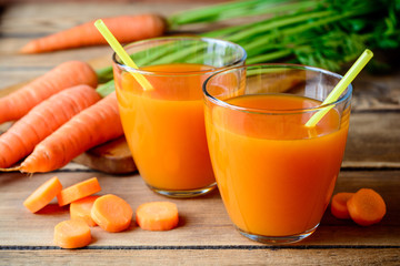 Fresh carrot juice in glasses on rustic wooden table.