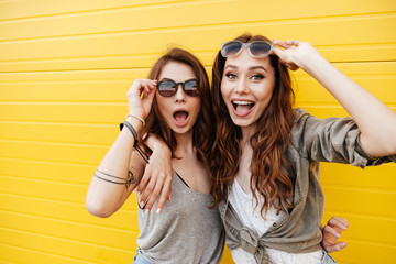 Poster - Young happy women friends standing over yellow wall