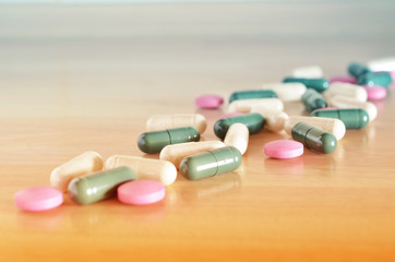 Wall Mural - Pharmacy theme. Multicolored pills on a brown wooden surface. Closeup.