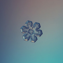 Real Snowflake Macro Photo: Small Snow Crystal Of Star Plate Type With Glossy Surface, Six Short, Broad Arms And Complex Inner Pattern. Snowflake Glittering On Smooth Blue Gradient Background.