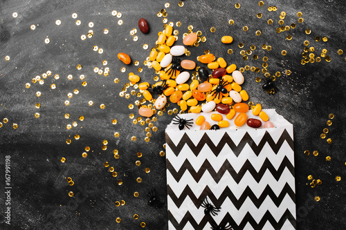 Fototapeta Halloween Party Trick of Treat Candy with candy flowing from party favor bag on dark wood background Flat lay, top view trendy holiday concept