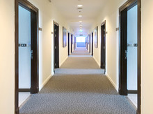 Blurred Corridor With Lots Of Dark Brown Doors. White Walls And Ceiling Concrete Floor. Concept Of Hotel Lobby.