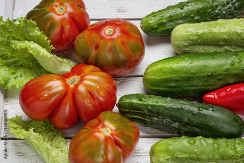 On a white wooden table, red tomatoes, cucumbers, lettuce and pepper Poster