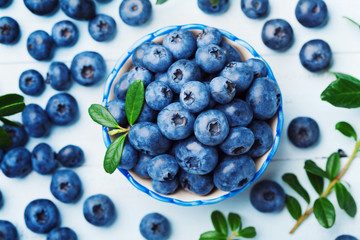 Wall Mural - Blueberry or great bilberry in bowl on blue wooden background top view. Organic superfood and healthy nutrition.