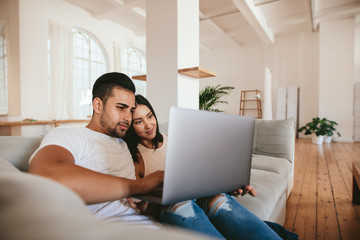 Wall Mural - Loving young couple using laptop at home