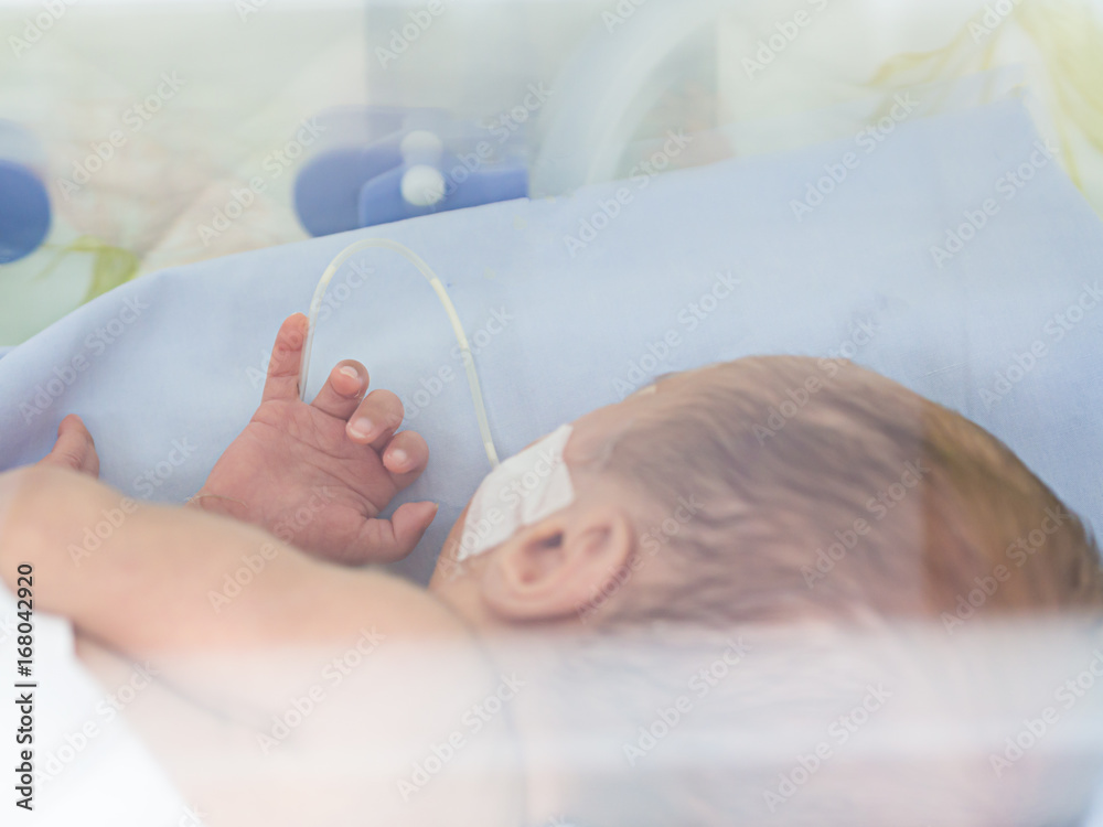 Sick newborn baby, infant in an incubator after preterm birth at intensive care unit or neonatal room at hospital - obrazy, fototapety, plakaty 