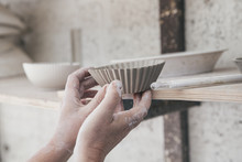 Hands Of A Ceramic Artist Placing A Bowl On A Shelf