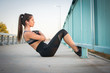 Young sporty woman doing sit ups on a sidewalk.