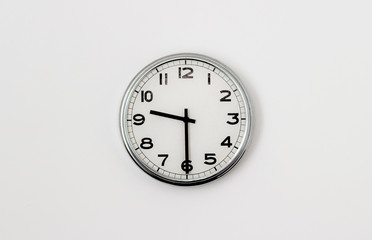 White Clock hanging on a white wall showing time 9:30