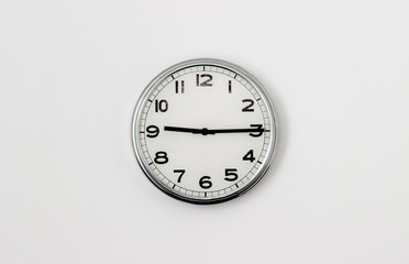 White Clock hanging on a white wall showing time 9:15