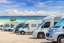 Close Up Motorhomes Parked In A Row On White Sand Beach And Blue Sky Background.