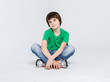 © Prostock-studio - Portrait of a cute boy sitting on the floor on white background