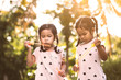 © pingpao - Two cute asian child girls having fun to play with bubbles together in outdoor at sunset