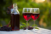 Glasses Of Elderberry Wine And Elderberries On Wooden Table