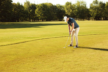 Male Golfer Putting Golf Ball On Green
