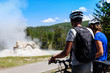 A couple of bikers, bicyclists watching a geyser in Yellowstone National Park