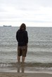 © Eva - Man in a hooded sweatshirt wading in the sea