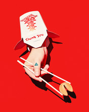 Hand Emerging From Takeout Container, Holding Fortune Cookie With Chopsticks, On Red Background, Conceptual