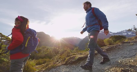new zealand hiking. young hiking couple walking on trail at routeburn track during sunny day. hikers