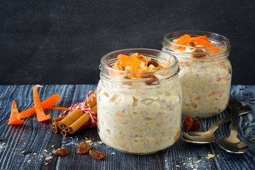 Wall Mural - carrot cake overnight oats with nuts and raisins in jars on a rustic dark background