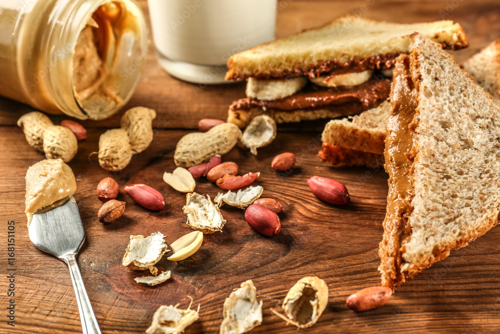 Tasty sandwiches with peanut butter and nuts on table