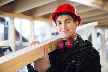 Carpenter Carrying Wood On Shoulder At Construction Site