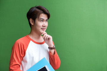 Poster - Young teenager man holding tablet computer and notebook and thinking action at green wall in university campus,Copy space for adding content of design for advertising in education campaign concept.