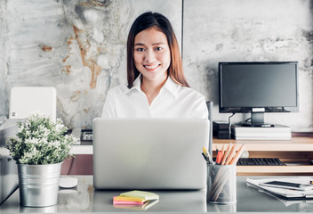 Poster - Asian businesswoman working with laptop computer on desk with smiling face,Happy office life concept,working woman at modern home office