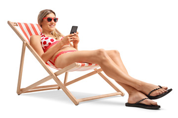 Poster - Young woman with a mobile phone in a deck chair