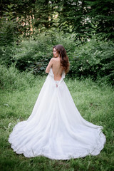  Look from behhind at bride taking off her dress standing in the garden