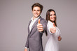 © F8  \ Suport Ukraine - Two smiling happy business people in formalwear showing thumbs-up on gray background