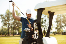 Handsome Male Golfer Taking Clubs From A Bag In A Golf Cart
