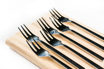 Metal forks on the wooden board over white background