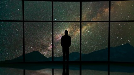 Wall Mural - The man stand near a panoramic window on the starry sky background. time lapse