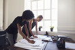 © Guerilla - Two young businesswomen looking at documents in an office