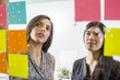 © Adam Hester/Blend Images - Women reading adhesive notes in office