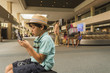 © Mark Edward Atkinson/Tracey Lee/Blend Images - Boy playing on smartphone while sitting at airport