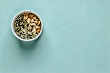 Wall Mural - Healthy eating, snack. Nuts and seeds in white bowl, closeup, flat position